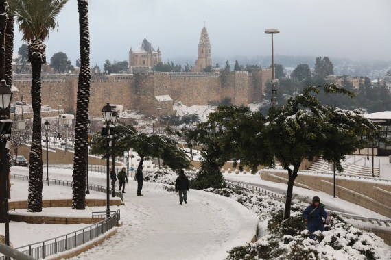 People walk in the snow after a snowstorm near Jaffa gate in the old city of Jerusalem, 27 January 2022. A regional winter storm called 'Elpis' hit Israel that has also affected Turkey and Greece