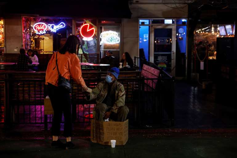 A woman hands a meal to a man stating to be a homeless veteran along Downtown 8th Street in Boise, Idaho, United States