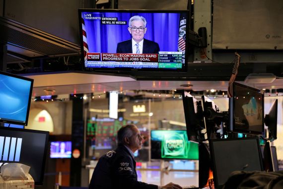 Federal Reserve Chair Jerome Powell is seen delivering remarks on a screen as a trader works on the trading floor at the New York Stock Exchange