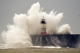 Waves crash over Newhaven Lighthouse and the harbour wall in Newhaven, southern England