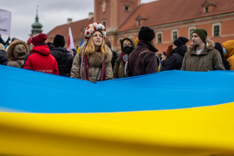 Protesters wave Ukrainian and Polish flags during a demonstration for peace 