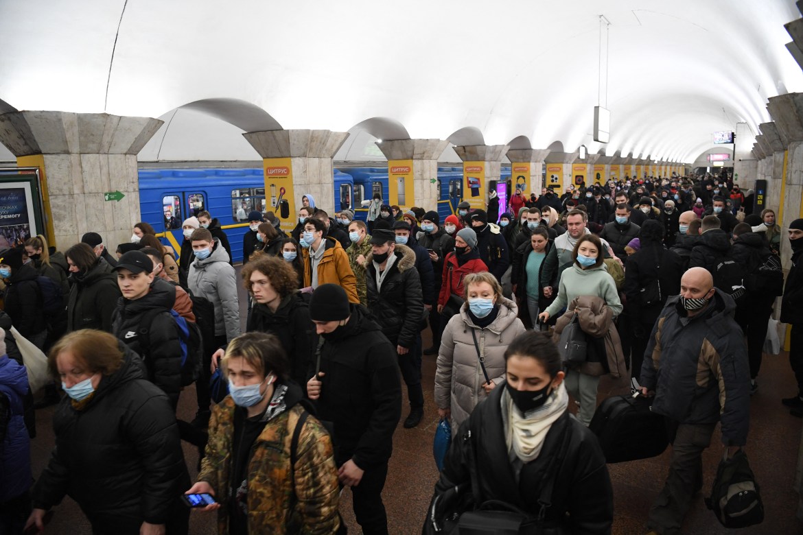 People, some carrying bags and suitcases, walk at a metro station in Kyiv