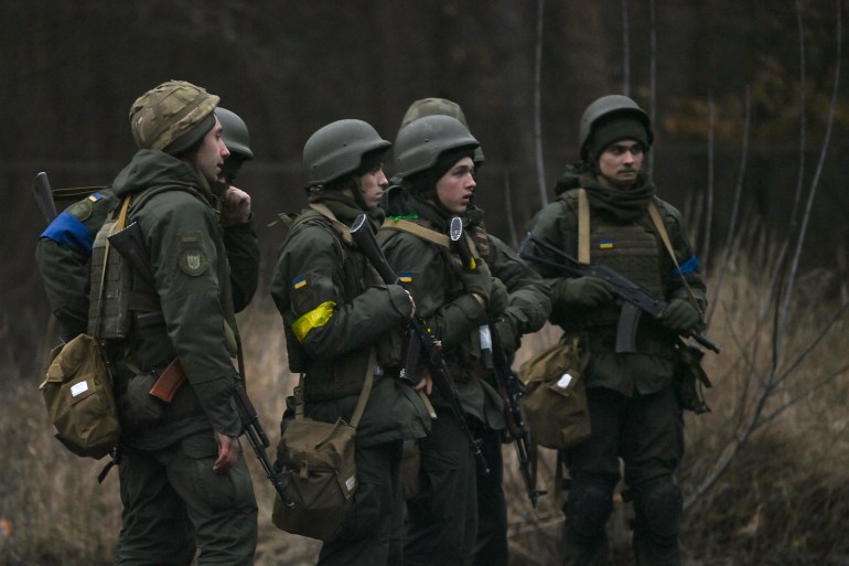 Ukrainian servicemen stand on the north of Kyiv.