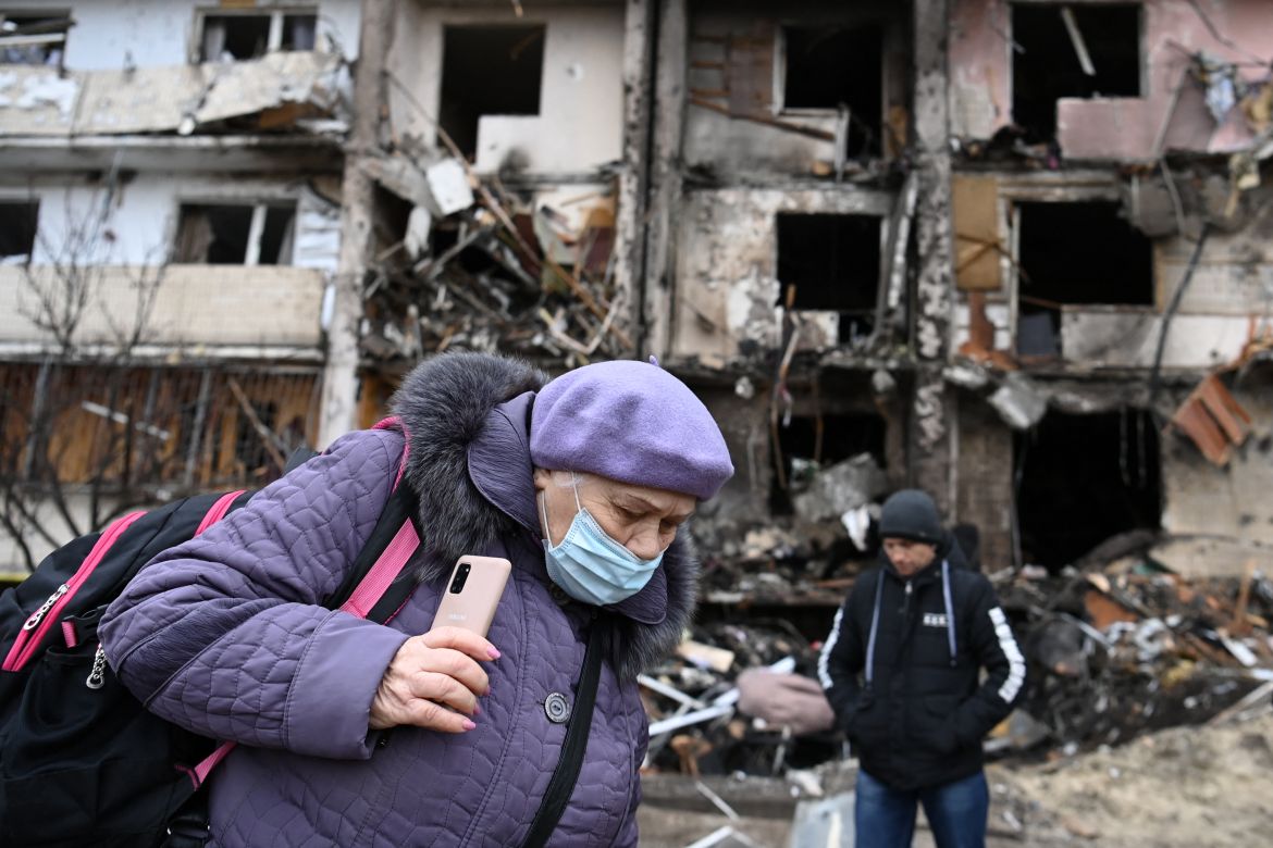 A woman with a backpack walks in front of a damaged residential building at Koshytsa Street, a suburb of the Ukrainian capital Kyiv,