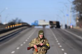 An Ukrainian service member patrol the empty road on west side of the Ukrainian capital of Kyiv in the morning of February 26, 2022. - Ukrainian soldiers beat back a Russian attack in the capital Kyiv only hours after President Volodymyr Zelensky warns Moscow would attempt to take the city before dawn. (Photo by Daniel LEAL / AFP)