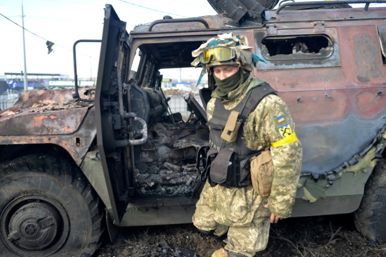 An Ukrainian Territorial Defence fighter examines a destroyed Russian infantry mobility vehicle GAZ Tigr after the fight in Kharkiv