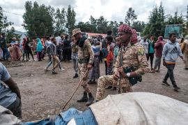Members of special force of the Amhara police stand next to sacks of food during food distribution for internally displaced people from Amhara