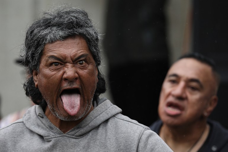 a Maori man sticks his tongue out as part of a Haka during a protest against COVID measures in New Zealand