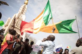 Men wave Malian national flags during a mass demonstration in Bamako, on January 14, 2022, to protest against sanctions imposed on Mali and the Junta by the Economic Community of West African States (ECOWAS).