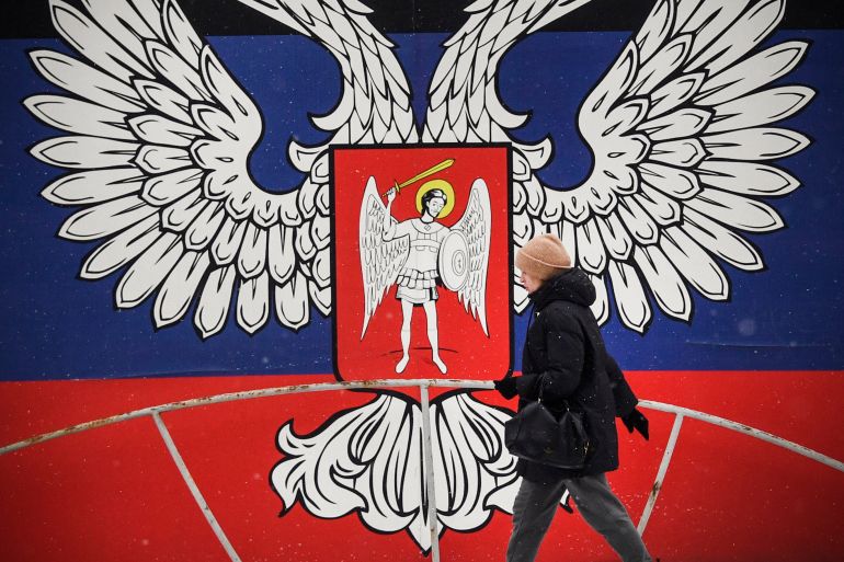 In this file photo taken on January 19, 2022, a pedestrian walks past a huge state emblem of the self-proclaimed Donetsk People's Republic in Donetsk, eastern Ukraine