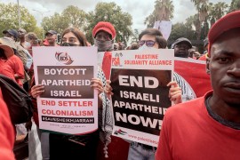Members of General Industrial Workers Union of South Africa hold up posters against Israeli apartheid