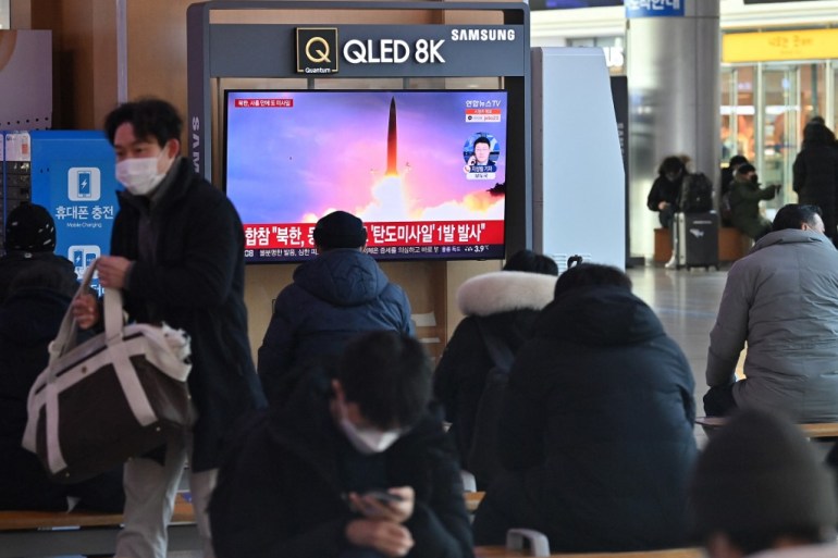 People watch a television screen showing a news broadcast with file footage of a North Korean missile test, at a railway station in Seoul.