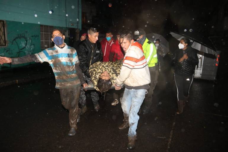 People carry an injured man during the search for victims after a landslide caused by heavy rains in Quito