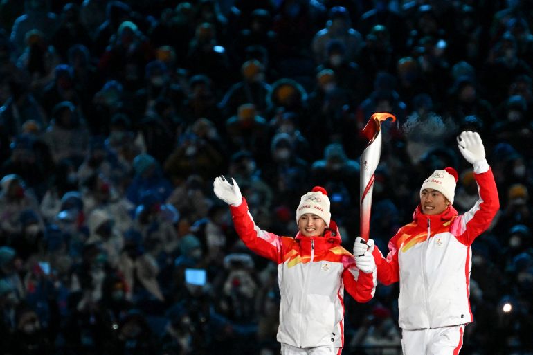 Chinese torchbearer athletes Dinigeer Yilamujian (L) and Zhao Jiawen hold the Olympic flame