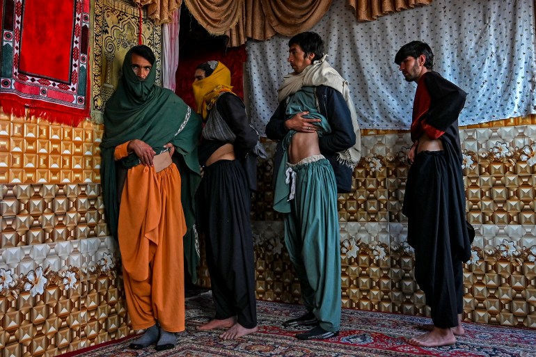 In this photo taken on February 4, 2022, Afghan men who sold their Kidney earlier in an attempt to save their family from starvation, shows the operation scars marks inside their house in Sayshanba Bazaar in the Injil district of Herat province. - Jobless, debt ridden, and struggling to feed his children, Nooruddin felt he had no choice but to sell a kidney -- one of a growing number of Afghans willing to sacrifice an organ to save their families. (Photo by Wakil KOHSAR / AFP)