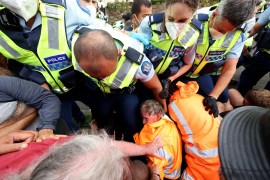 Police in high vis vests block the way of protesters in bright orang jackets in the grounds of New Zealand's parliament building