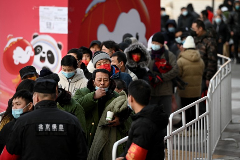 People queue to enter a Beijing Winter Olympics souvenir store at Wangfujing shopping mall complex in Beijing [Noel Celis/AFP]