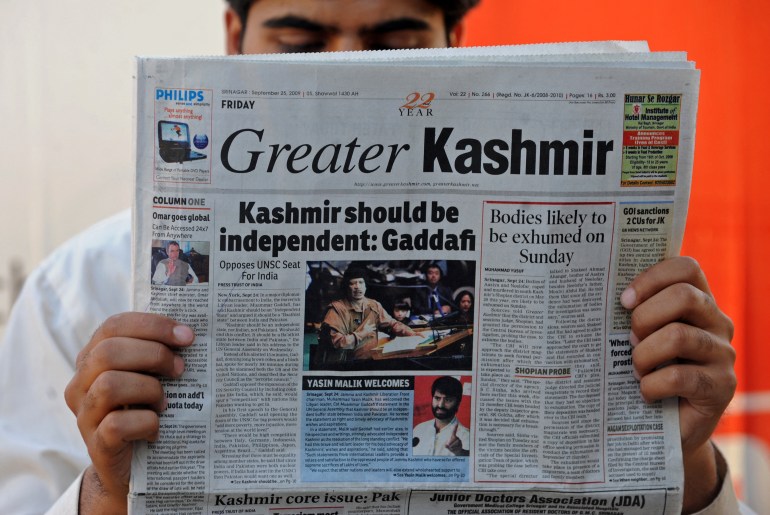 A Kashmiri man reads a newspaper featuring an image of Libyan leader Moamer Kadhafi addressing The United Nations General Assembly