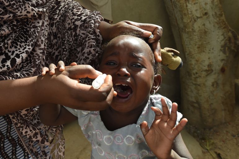 A young girl in Nigeria squirms and cries as a health worker gives her the polio vaccine