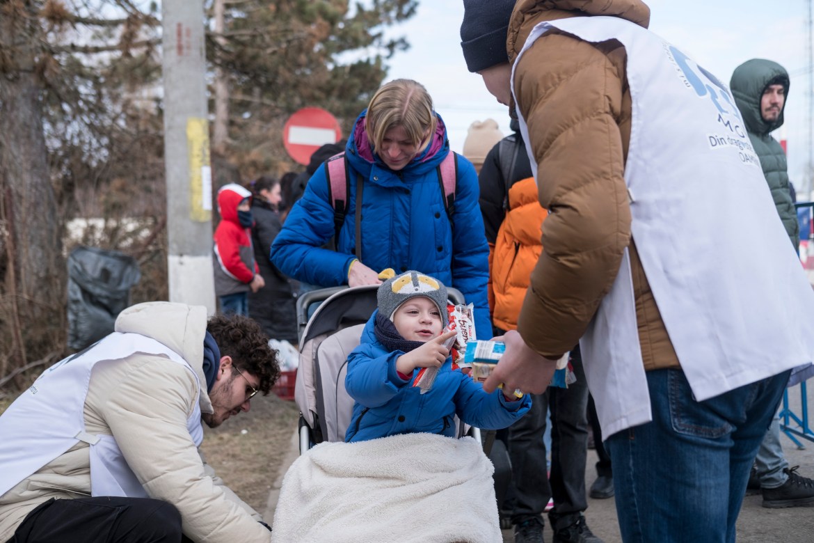 A volunteer gives sweets to a child shortly after him and his mother arrived in Romania.