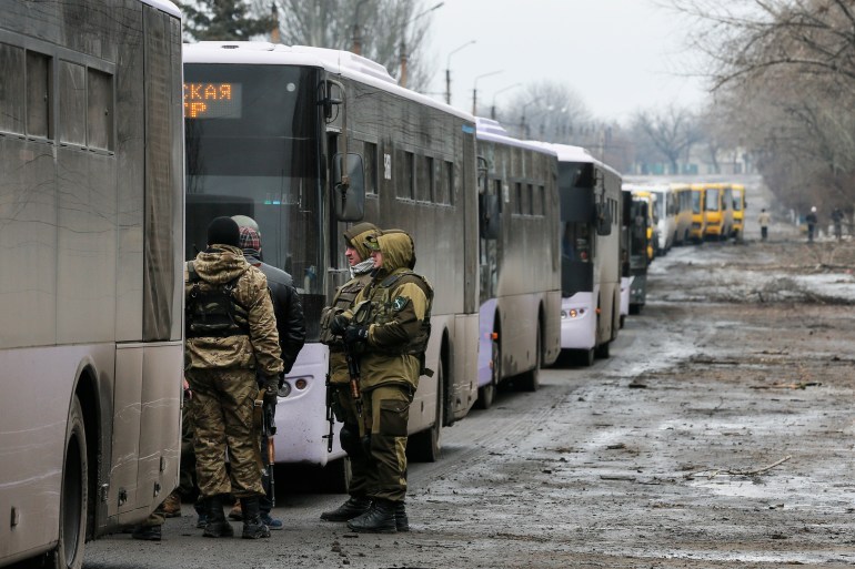 Members of the armed forces of the separatist self-proclaimed Donetsk People's Republic are seen standing next to buses