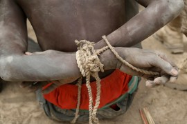 A prisoner, suspected of being a member of the Boko Haram group, sits with his arms tied behind his back in the field base of Chadian soldiers in Gambaru, Nigeria