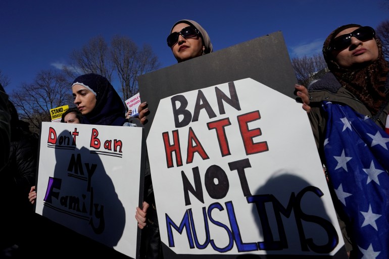 Woman carrying sign saying ban hate not Muslims