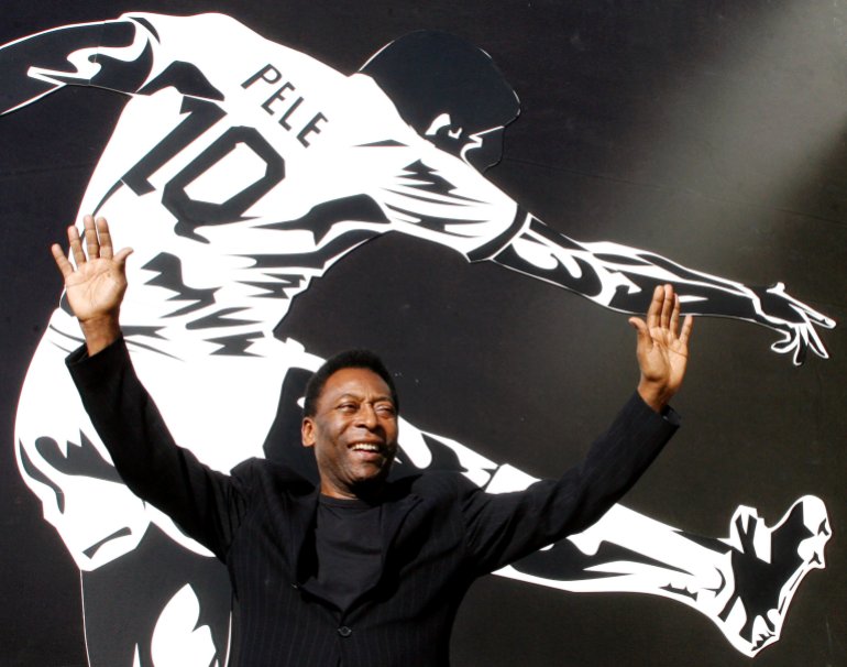 Pele poses for a photo in front of a mural