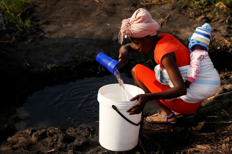 A woman with a baby on her back collects water in Mabvuku, a highly-populated suburb in Harare, Zimbabwe