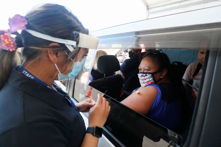 A woman in a car receives her COVID vaccination at a drive through centre in New Zealand