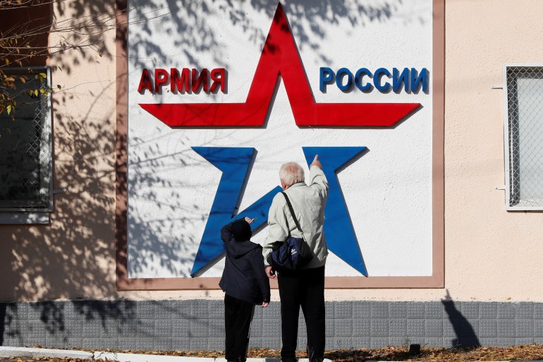 Local residents look at a banner on the Operational Group of Russian Forces headquarters in Tiraspol