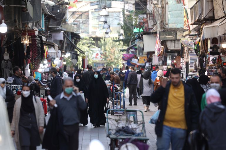 Iranians walk down a market street in Tehran, Iran