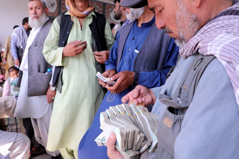 Afghan money exchange dealers wait for customers at a money exchange market, following banks and markets