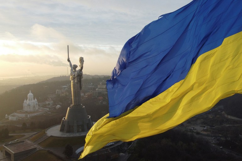 Ukraine's biggest national flag on the country's highest flagpole and the giant 'Motherland' monument are seen at a compound of the World War II museum in Kyiv