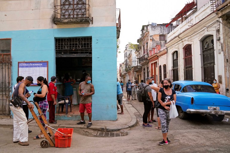 People wait outside of a food distribution, in Havana, Cuba