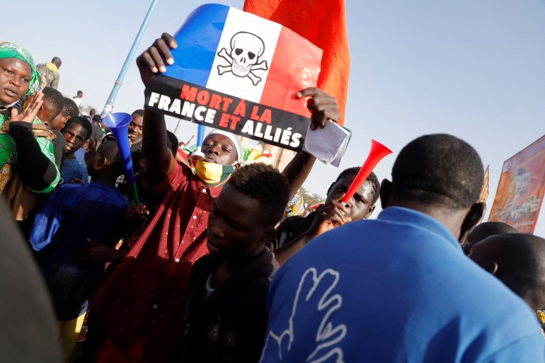 Protesters hold a placard of a French flag with a skull and bones drawn on top at an anti-French rally in Mali