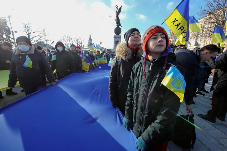 A crowd of Ukrainian protesters demonstrate outside while holding up Ukrainian flags