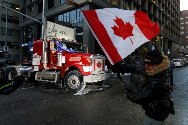 A person waves a Canadian flag in front of a truck