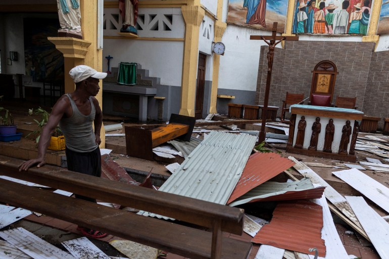 A local man is standing inside a damaged church after Cyclone Batsirai