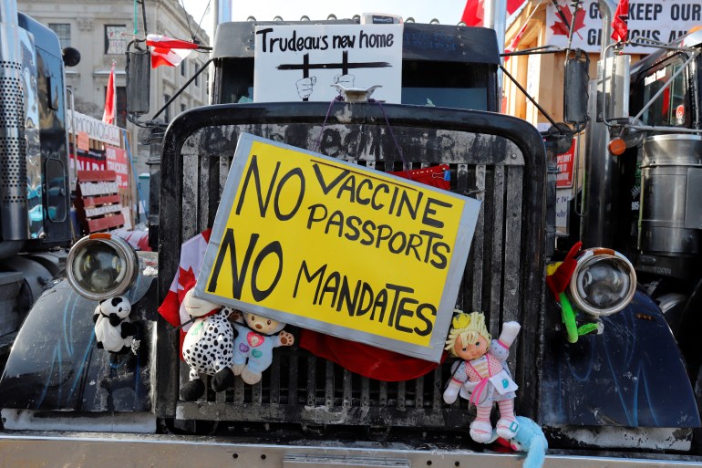 The front grille of a truck is pictured with yellow and white protest signs and stuffed toys attached to it. It sits near Parliament Hill as truckers and their supporters continue to protest COVID vaccine mandates in Ottawa
