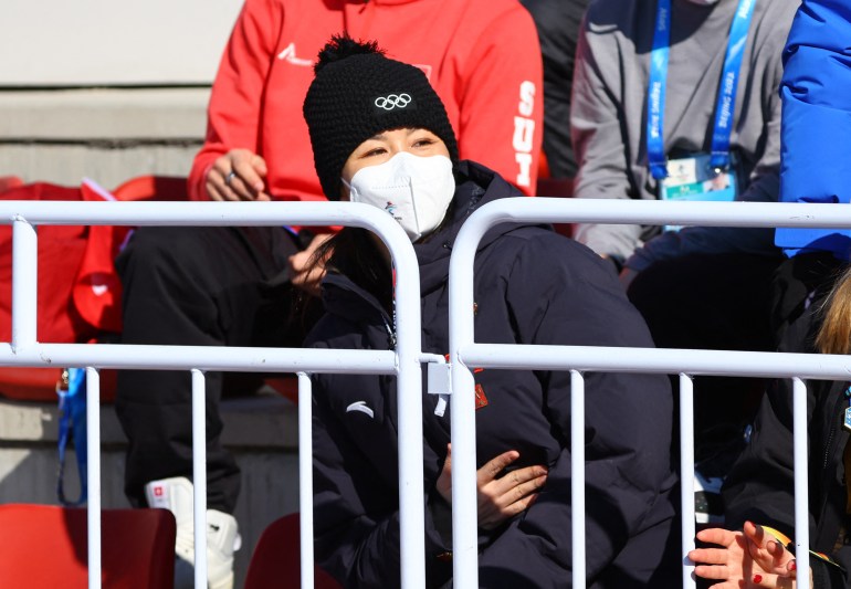 Tennis star Peng Shuai seen behind barriers watching the freeski Big Air event in black beanie with the Olympic rings and black coat