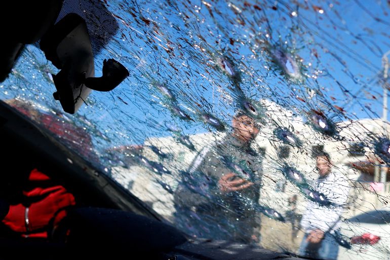 People look at a cracked windscreen with bullet holes at the scene where three Palestinian gunmen were killed by Israeli forces, in Nablus