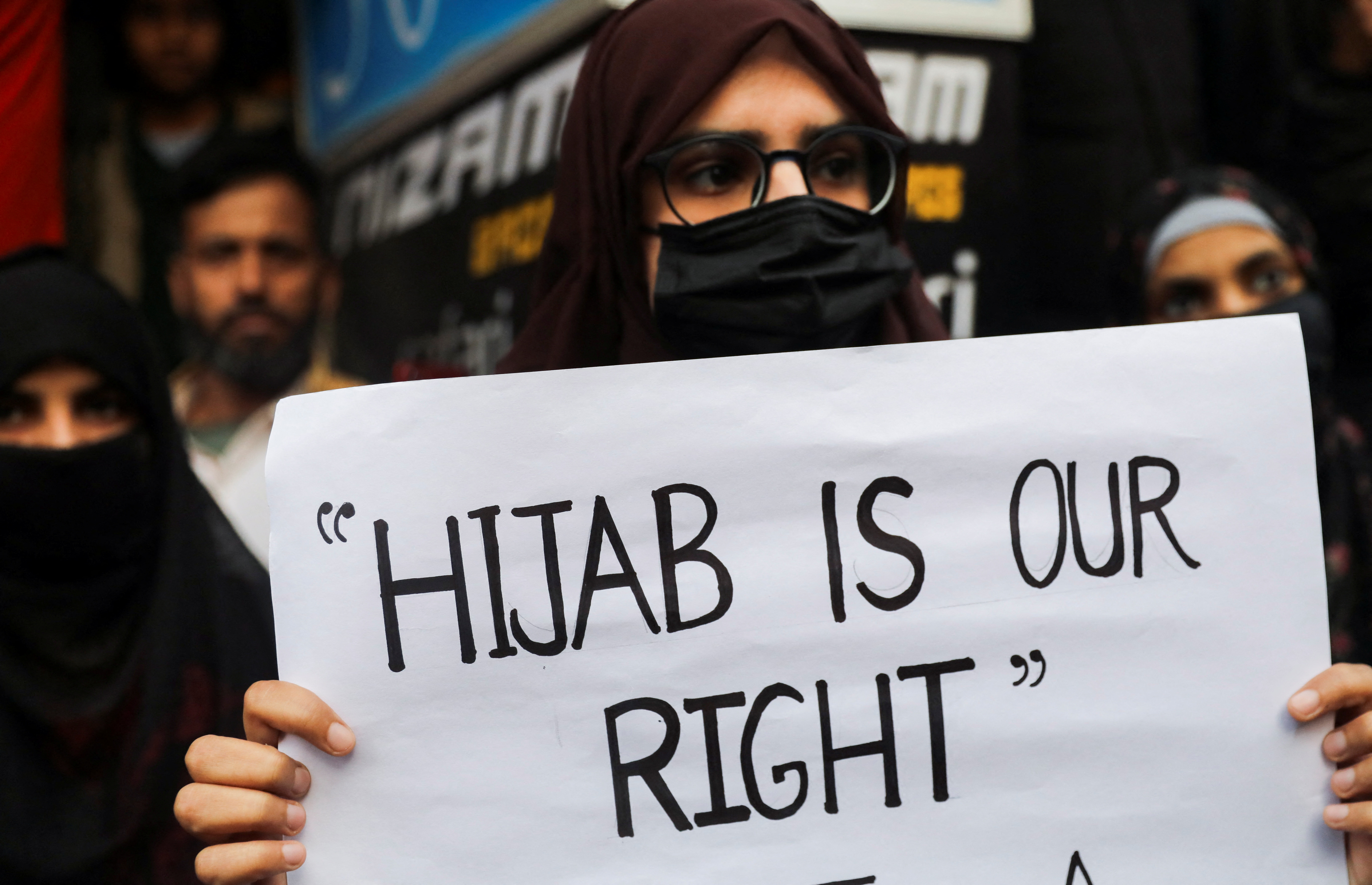 Una donna musulmana tiene un cartello mentre prende parte a una protesta organizzata da All India Majlis-e-Ittehadul Muslimeen (AIMM) contro il recente divieto dell'hijab in alcuni college dello stato del Karnataka, a Shaheen Bagh a Nuova Delhi, India