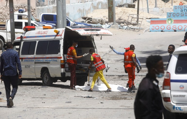Paramedics prepare to transport the body of an unidentified man killed in an explosion at a checkpoint near the presidential palace in Mogadishu, Somalia