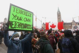 A counter-protester holds a sign outside Parliament in Ottawa
