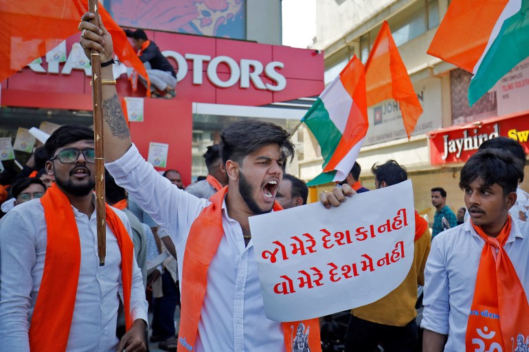 An activist of Bajrang Dal, a Hindu hardline group, shouts slogans in front of a KIA Motors showroom during a protest over their Pakistani partners' tweet in support of Kashmir, in Ahmedabad, India, February 12, 2022. The placard reads: "One who is not with my country, should not be in my country". REUTERS/Amit Dave