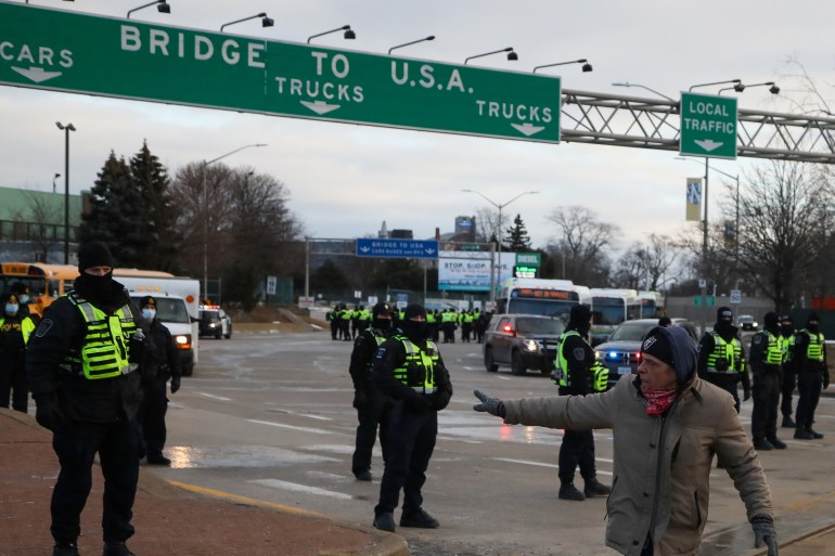 Police officers stand guard on a road leading to the bridge to the US