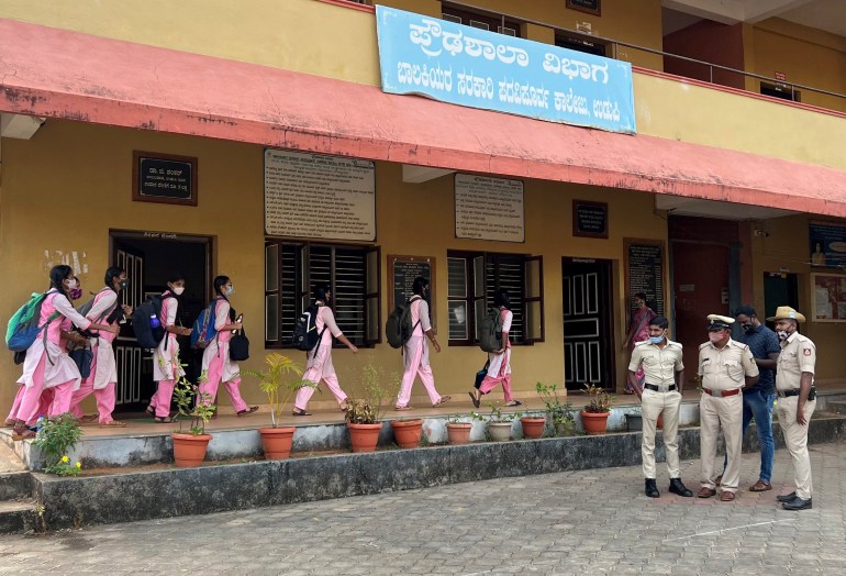 Schoolgirls arrive to attend their classes as police officers stand inside the premises of a government girls school after the recent hijab ban, in Udupi town in the southern state of Karnataka, India