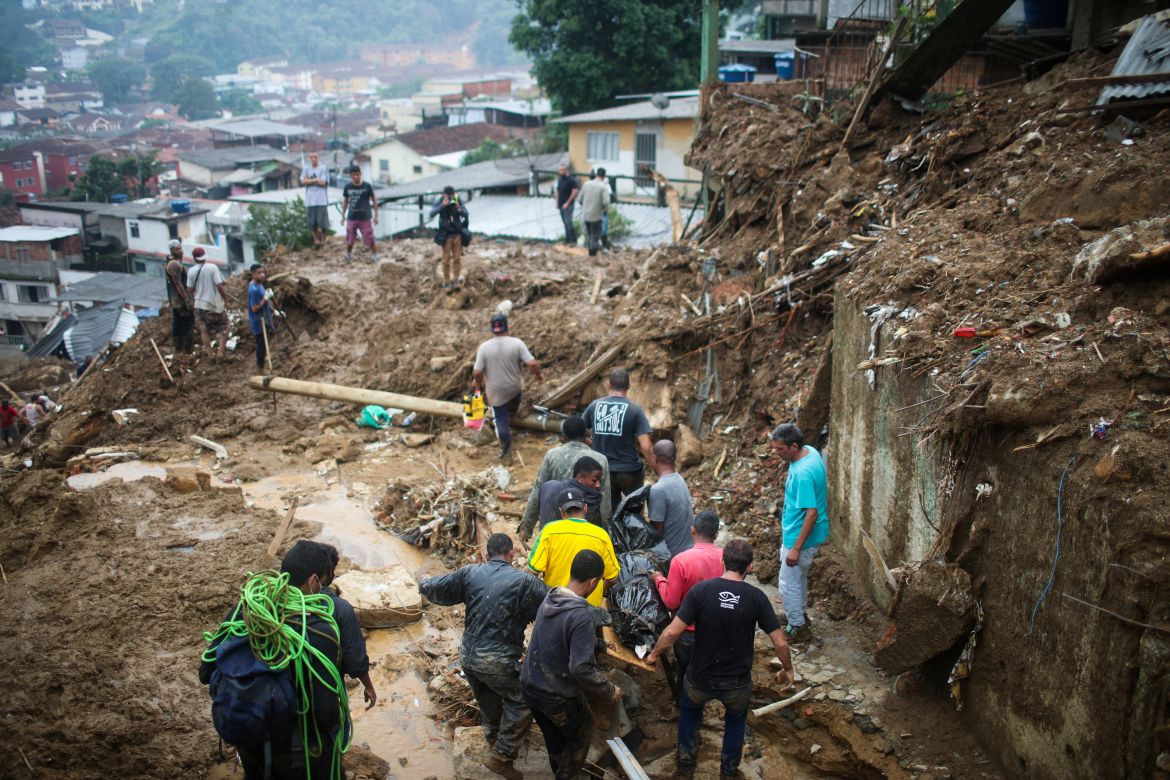 Men carry a body at a mudslide at Morro da Oficina after pouring rains in Petropolis