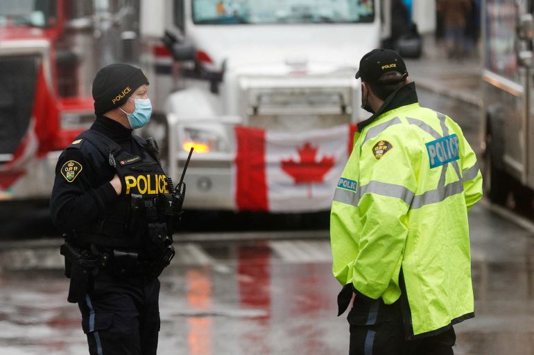 Two police officers stand near some protesters' trucks in Ottawa